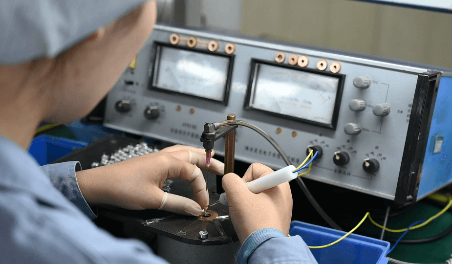 Worker testing electret microphone sensitivity using precision testing equipment